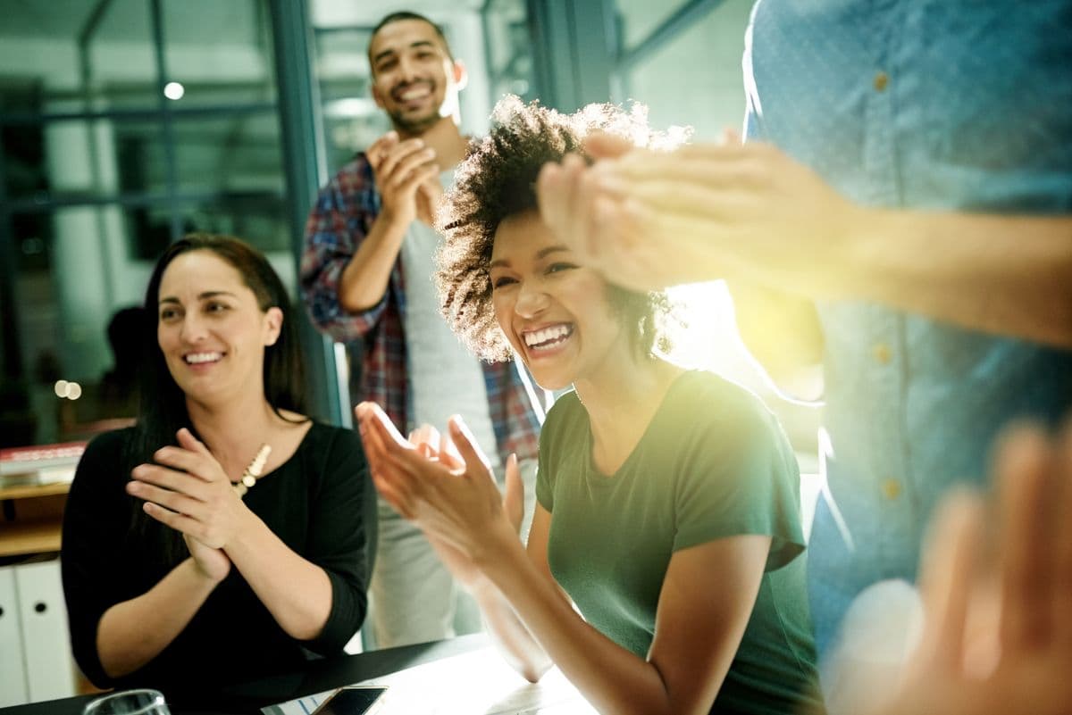 Diverse group of people clapping and laughing.