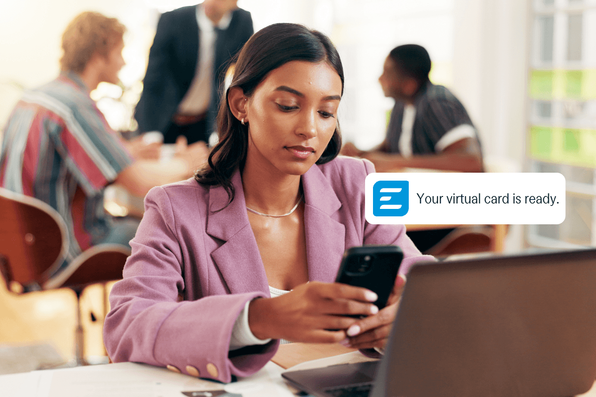 Woman looking at her phone, receiving a notification that reads "Your virtual card is ready."