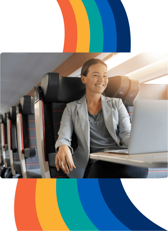 a woman is smiling while using a laptop on a train