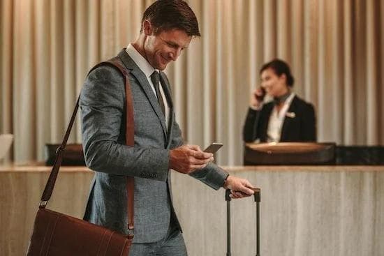 a man in a suit is looking at his cell phone in a hotel lobby .