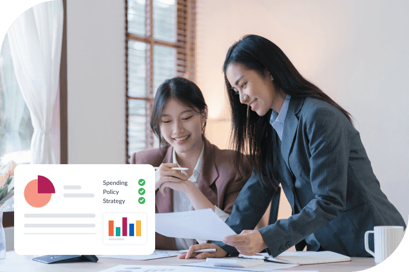 Two smiling businesswomen review documents, with an overlaid dashboard showing financial charts and policy status.