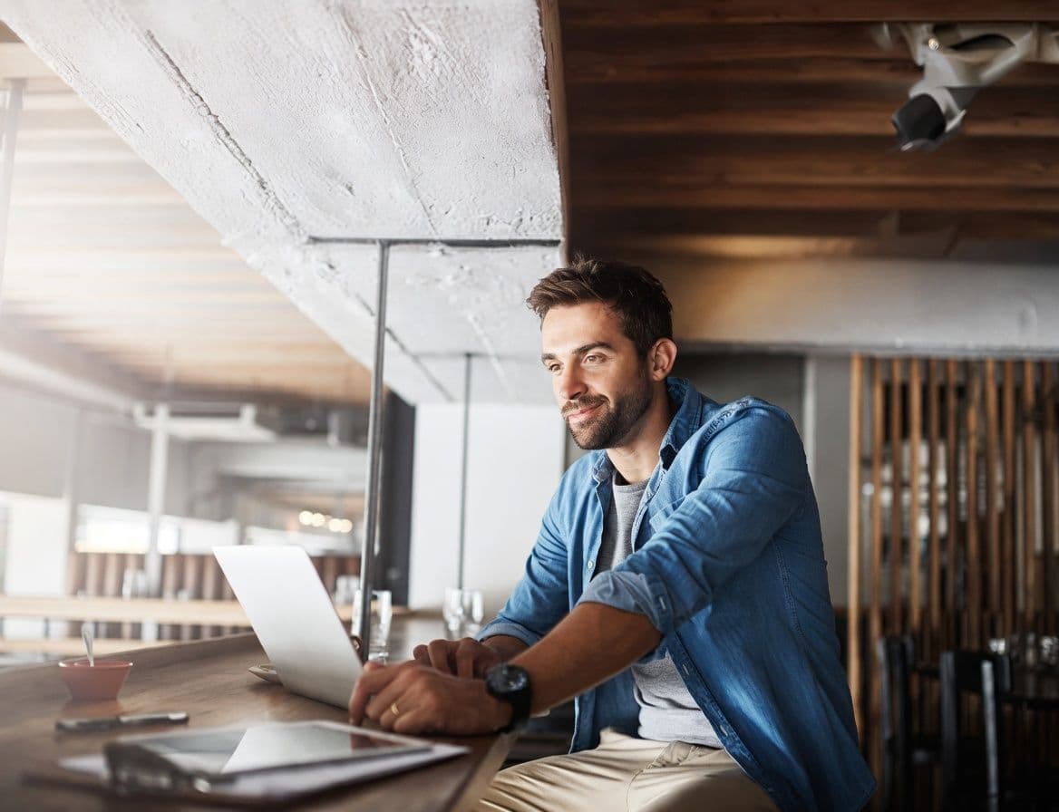 a man is sitting at a table using a laptop