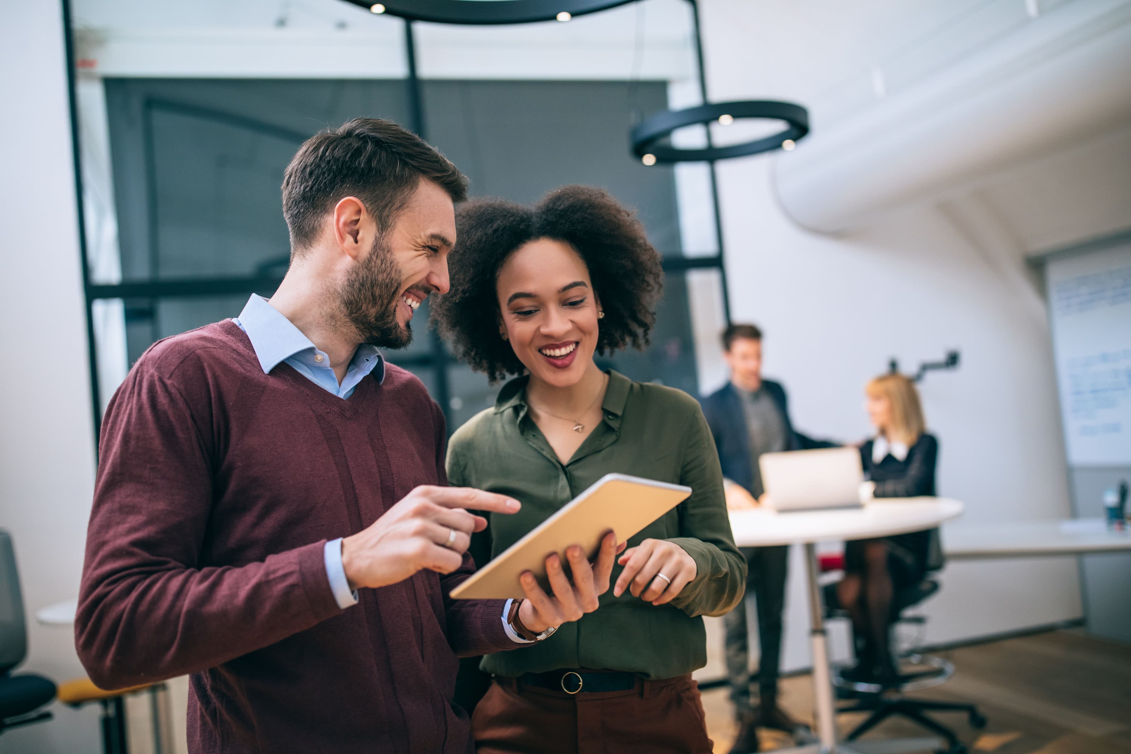 a man and a woman are looking at a tablet in an office .