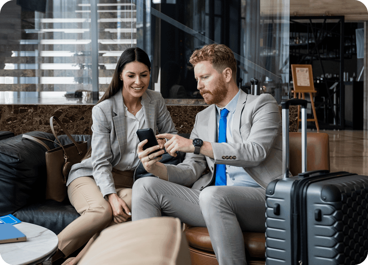 a man and a woman sit on a couch looking at a cell phone