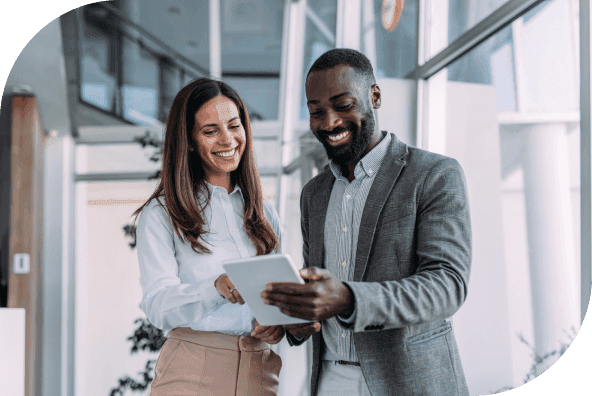 Two smiling business professionals looking at a tablet.