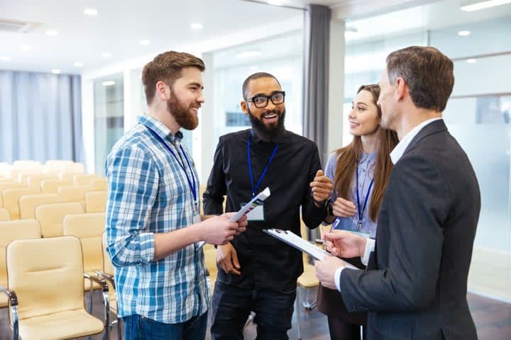 a group of people are standing in a room talking to each other .