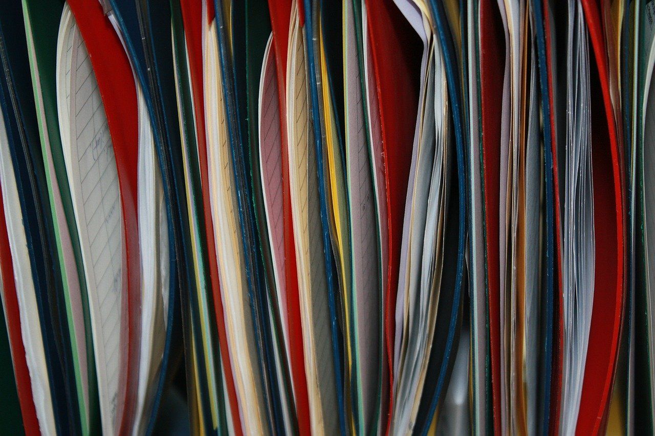 Colorful spines of tightly packed binders and folders.