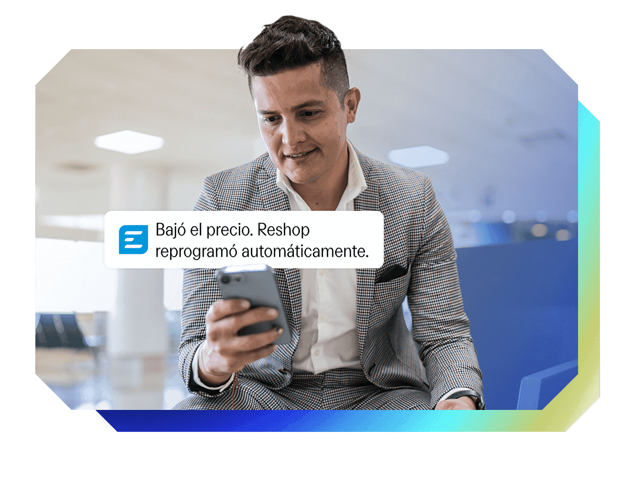 Smiling man in a suit looking at a phone showing a Reshop notification: "Price dropped. Reshop automatically rescheduled."