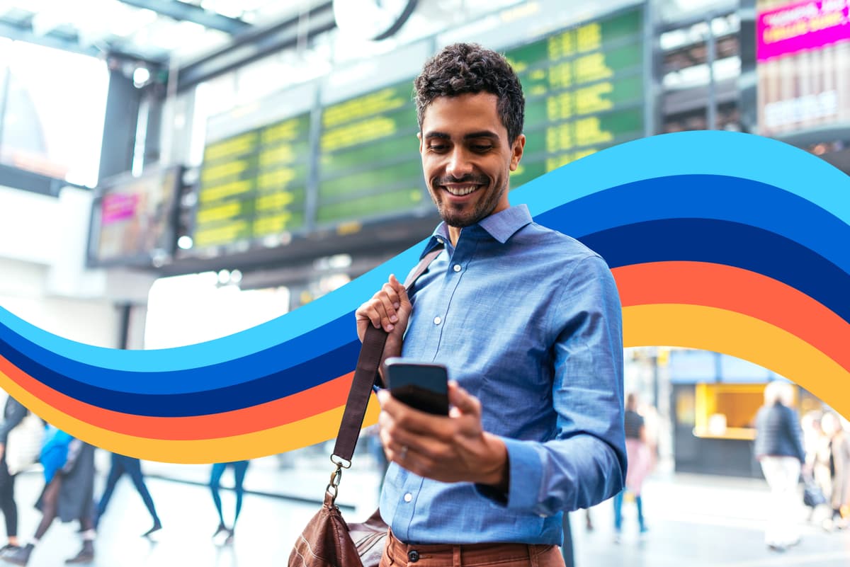 a man is looking at his cell phone at an airport .