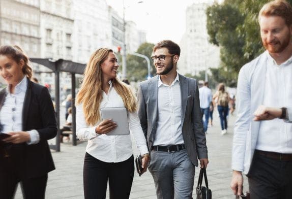 a group of business people are walking down a city street .