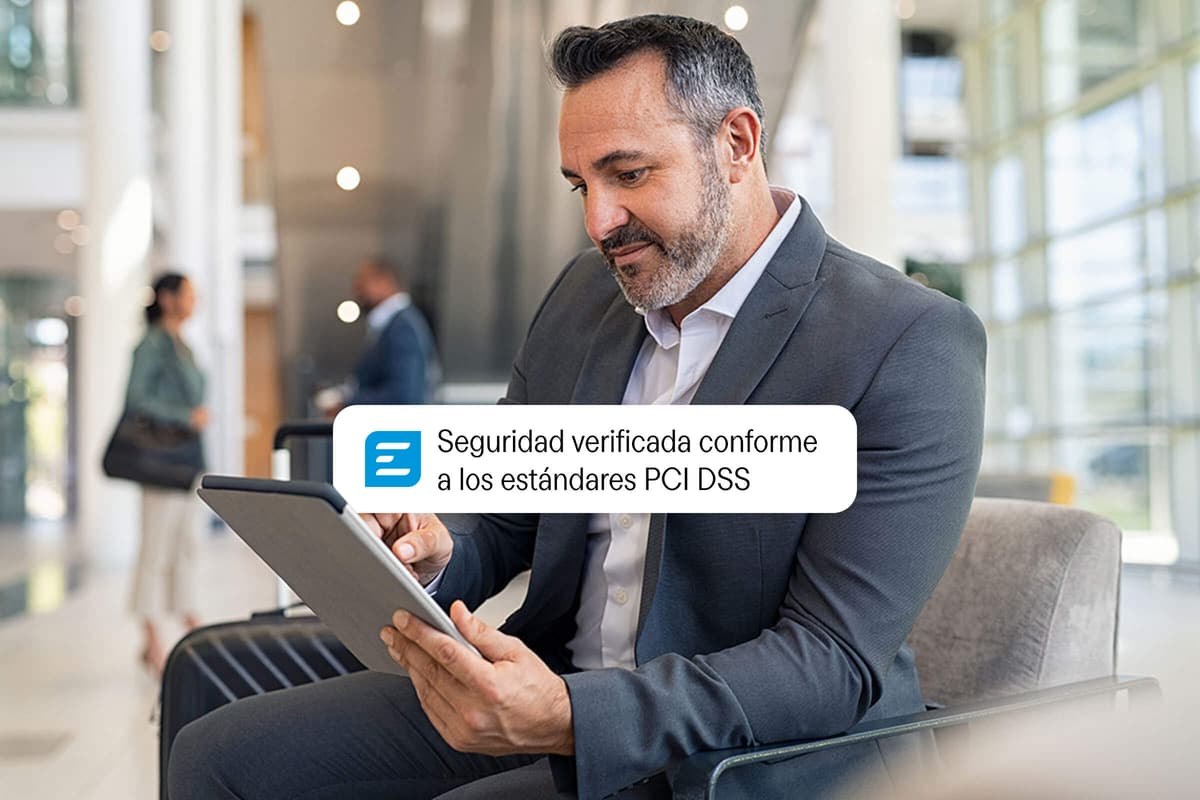 Man in a suit uses a tablet, showing a pop-up: "Seguridad verificada conforme a los estándares PCI DSS."