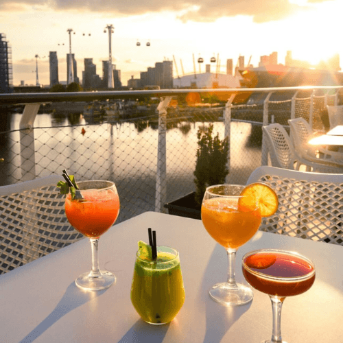 three drinks on a table with a city in the background