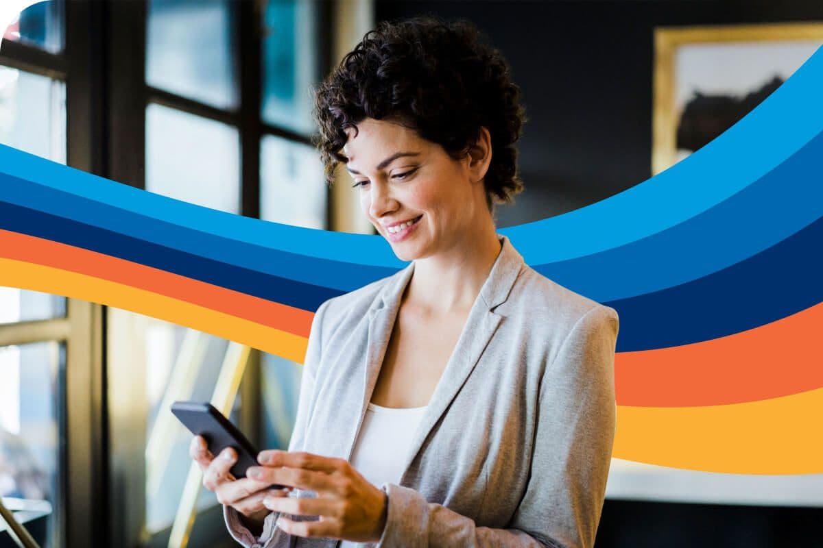 a woman is smiling while looking at her cell phone .