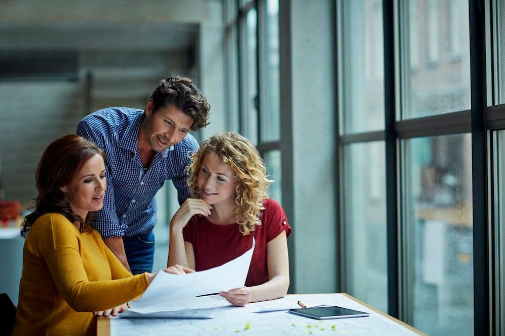 Three colleagues reviewing documents at a table.