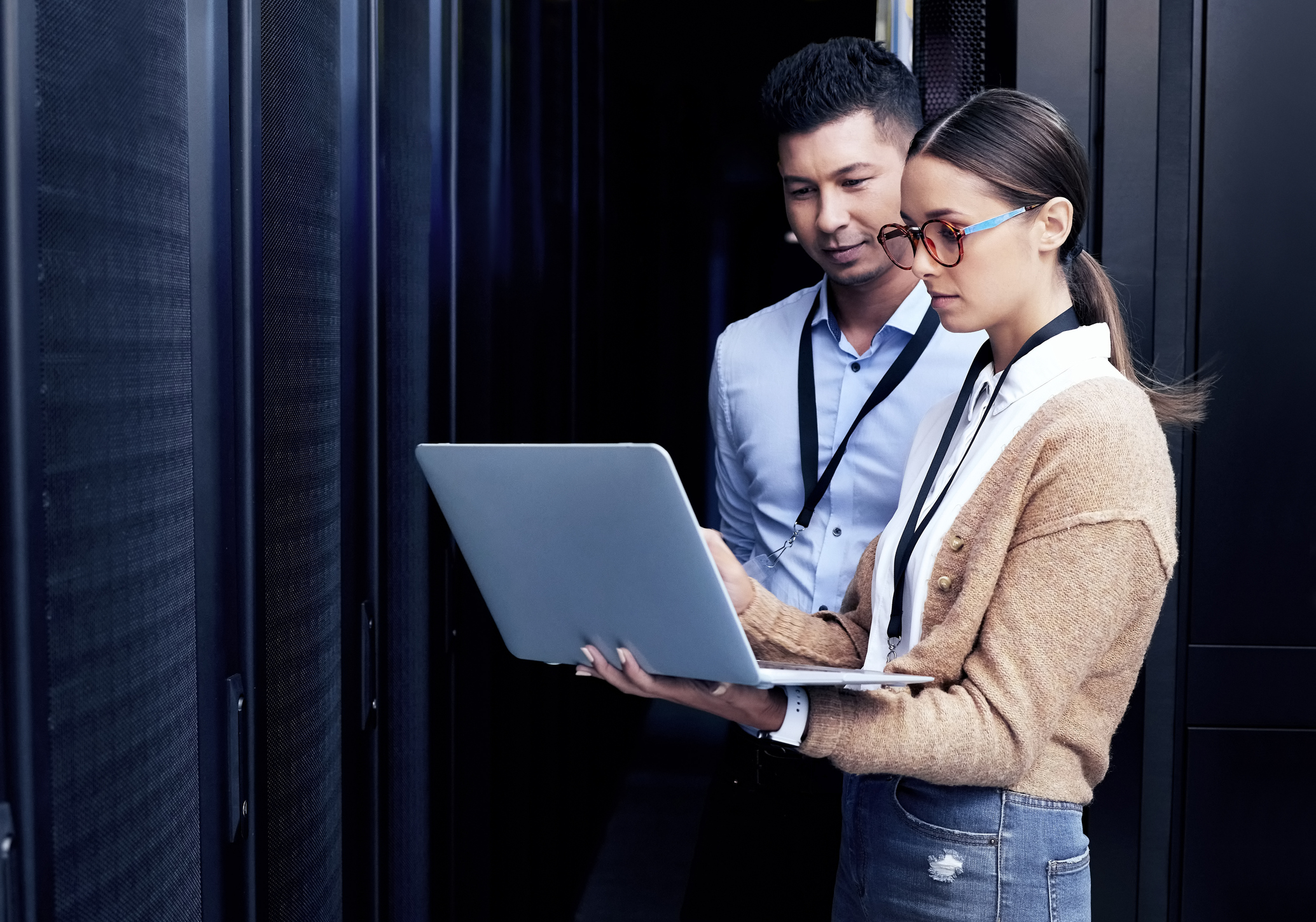 Two people on a laptop in a server room