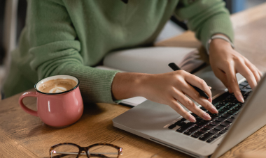 Woman typing on laptop with coffee mug